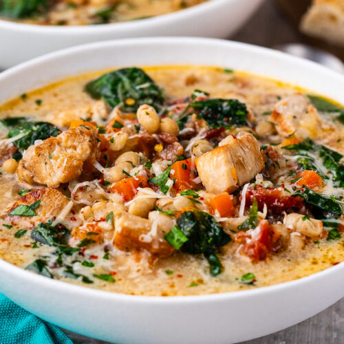 Creamy, chunky chicken and bean soup with spinach in a bowl topped with a little grated parmesan cheese.