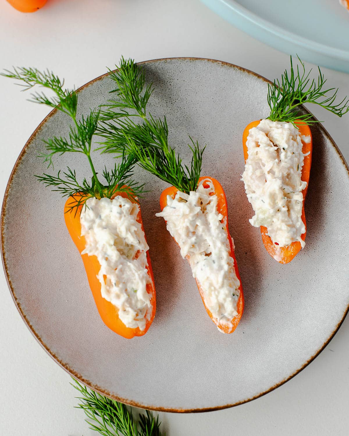Mini halved orange peppers filled with a creamy mixture and with a sprig of dill stuck in the top so they look like carrots.