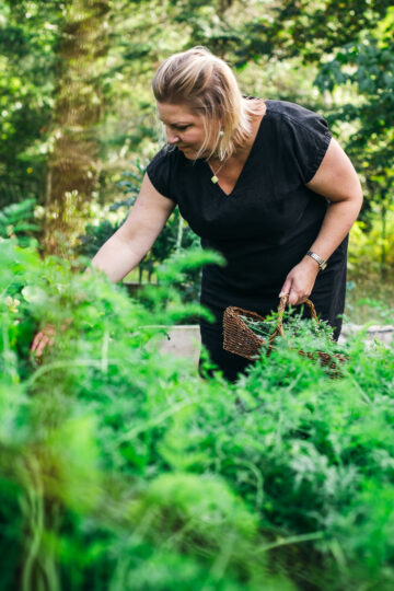Sabrina Currie in the garden with a basket full of herbs.