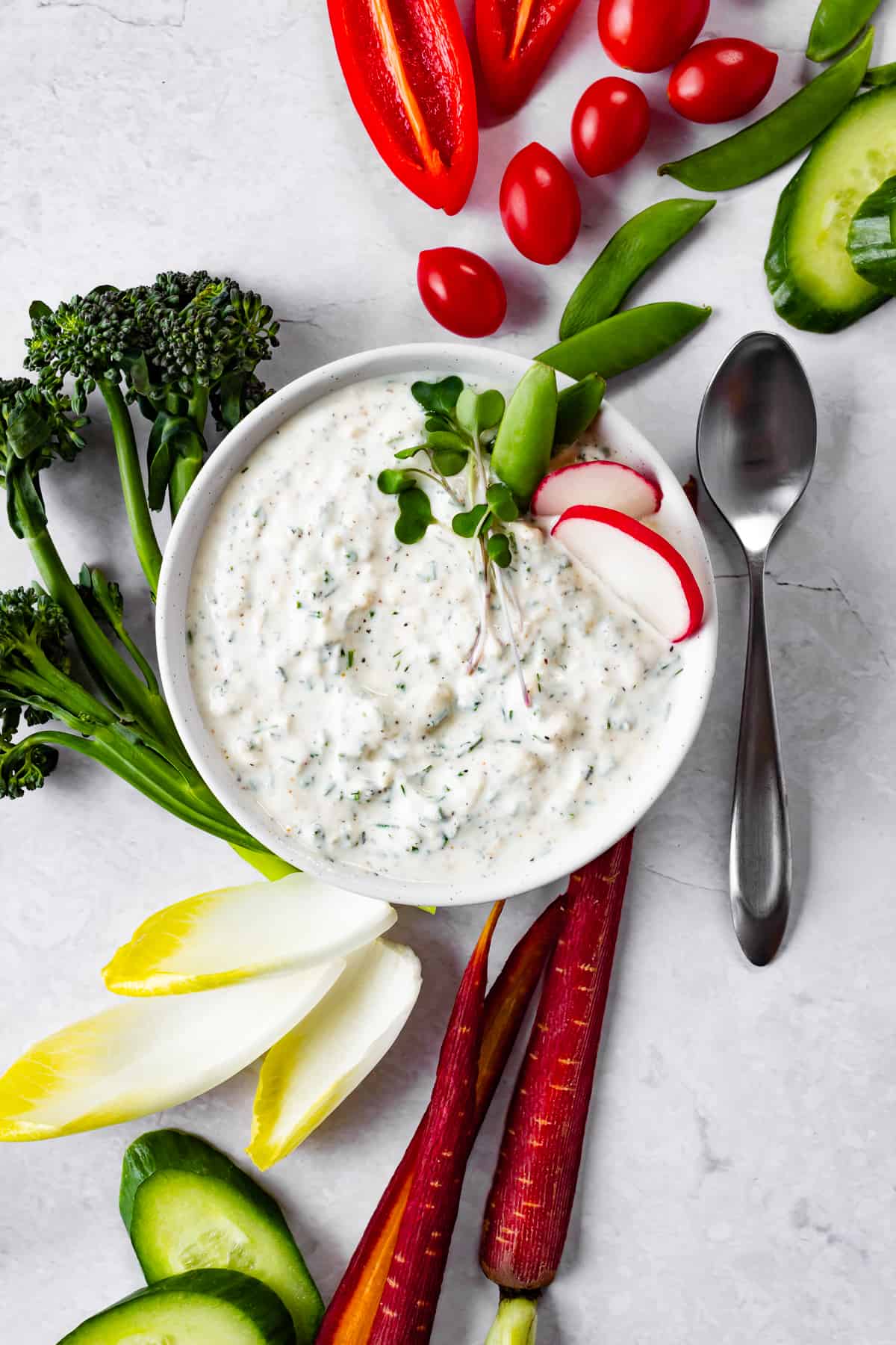 bright broccoli, red peppers, snap peas and radishes surround a bowl of herbed creamy dip.