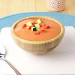 Chilled tomato and cucumber soup with a small bit of diced veggies on top as a garnish.