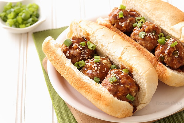 Meatballs in sub buns topped with a little chopped parsley.