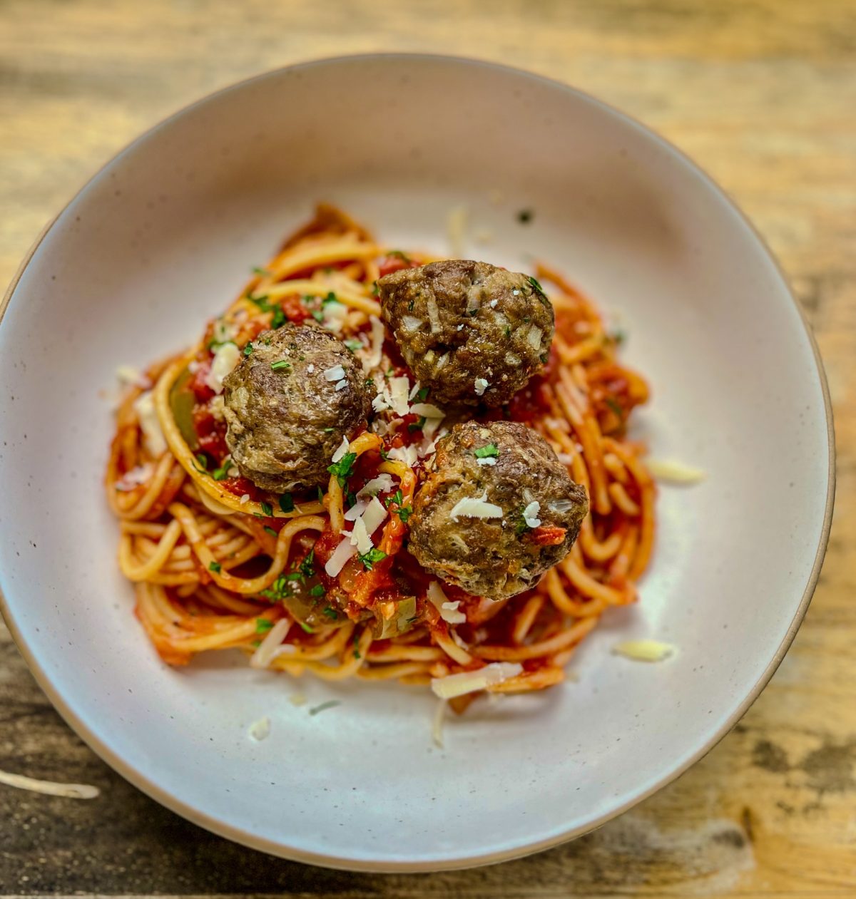 Three meatballs on top of spaghetti noodles and tomato sauce.