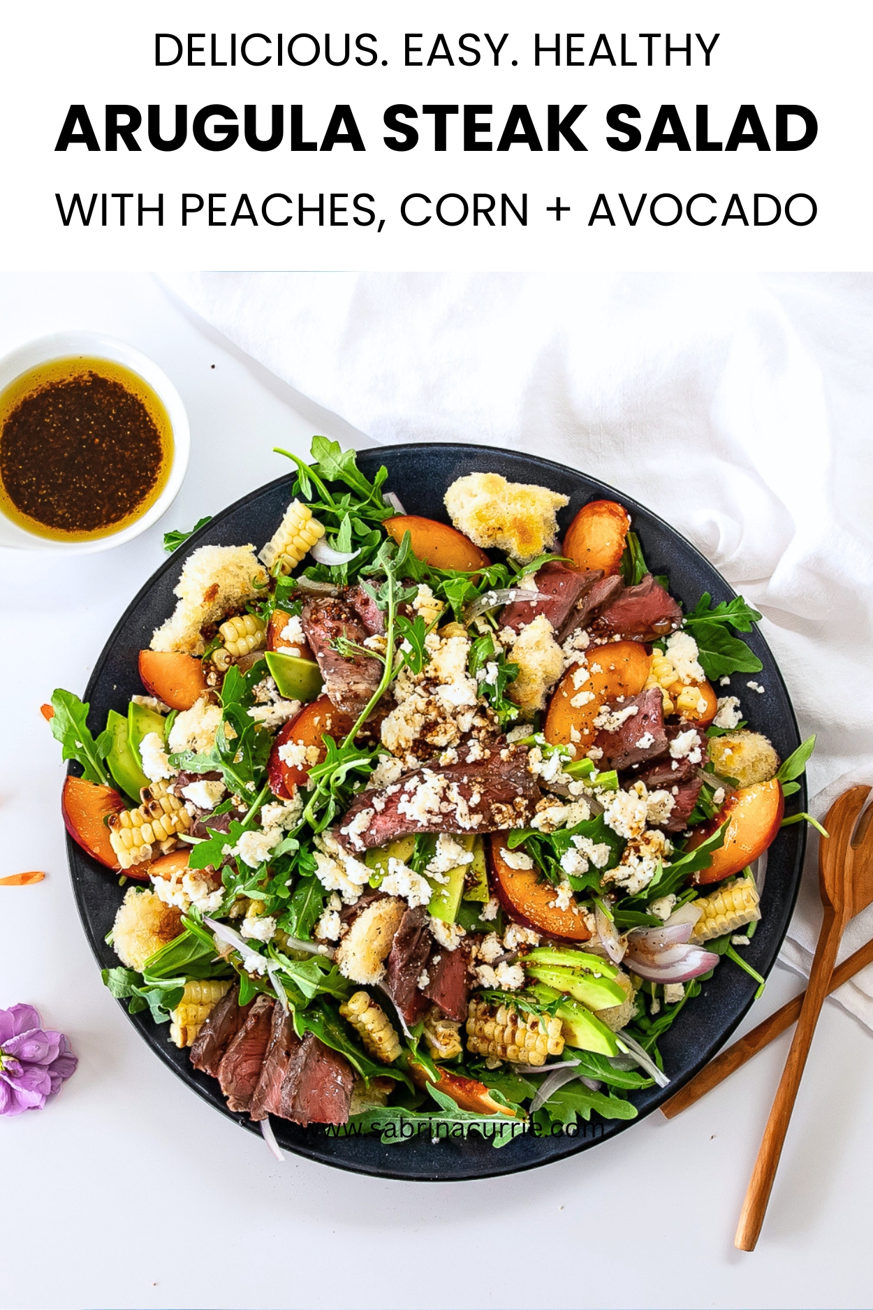 A pinterest image with the recipe title at the top and the finished arugula steak salad with peaches, corn and feta below on a plate.,