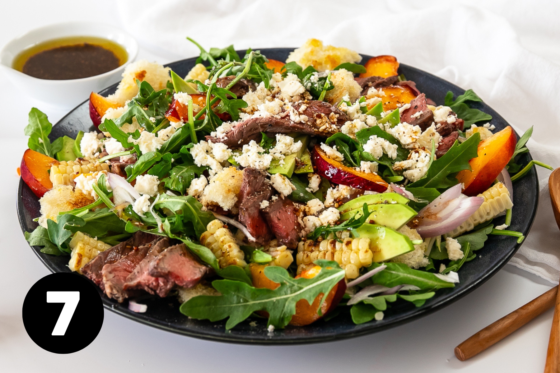The finished salad platter of greens, sliced peaches, avocado, steak and crumbled feta cheese.
