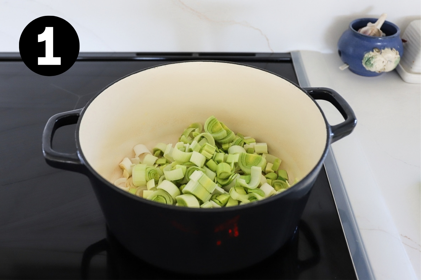 Sliced leeks in a large Dutch oven pot on the stove.