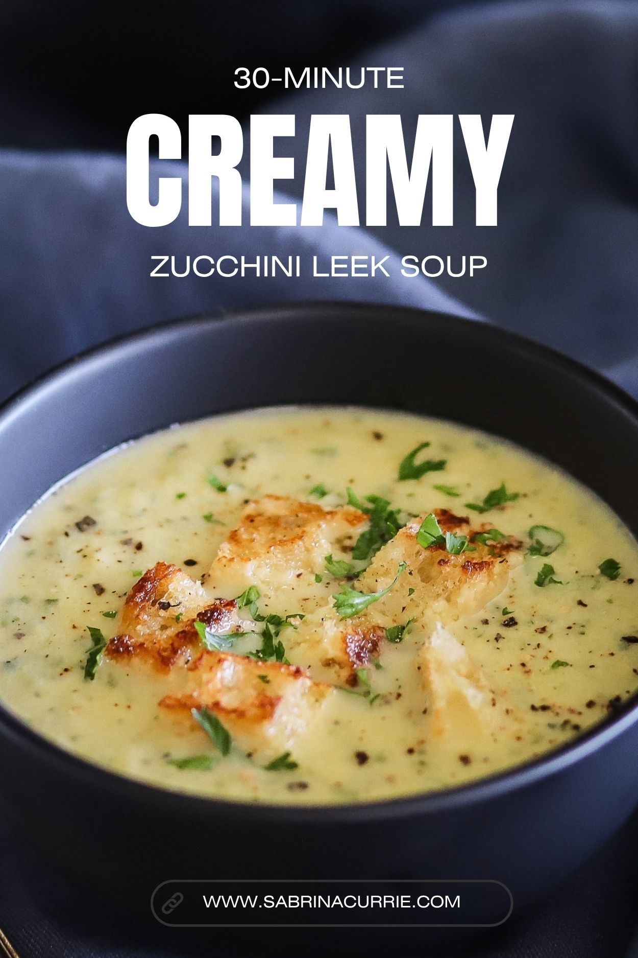 A bowl of parsley flecked creamy soup topped with toasted croutons.