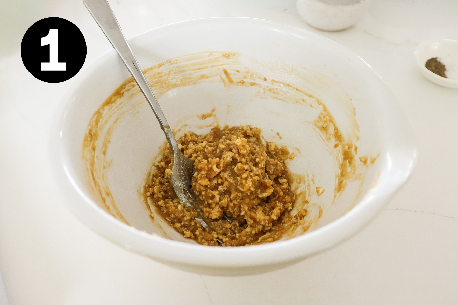 Mixture of miso and butter in a small white bowl with a spoon in it.