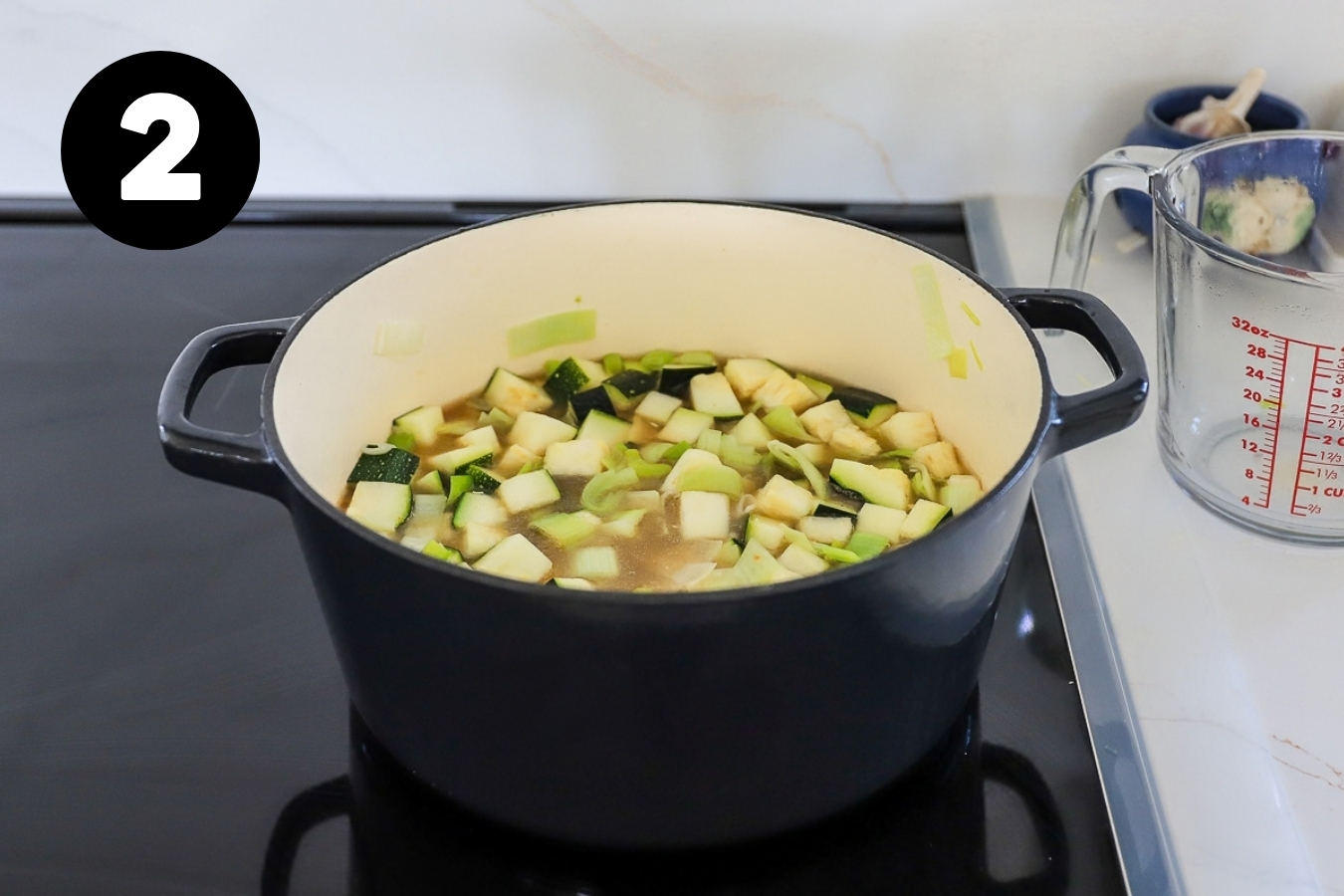 Chopped zucchini and broth in the pot with the leeks.