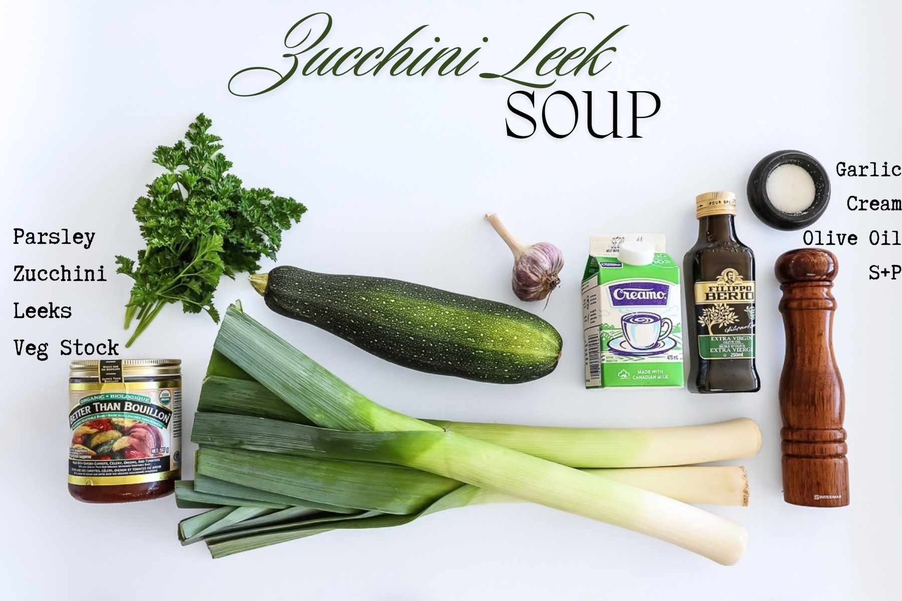 The ingredients for the soup on a countertop. Shown are parsley, vegetable bouillon base, a zucchini, 3 leeks, a bulb of garlic, a carton of cream, olive oil, salt and pepper.